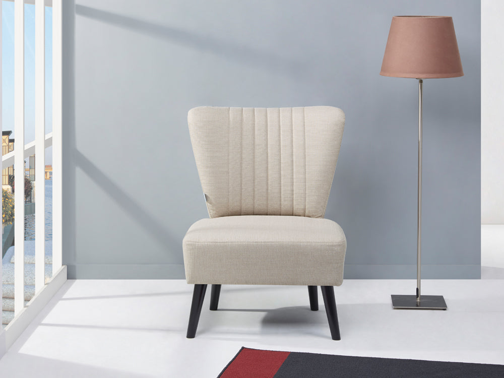 Anita Occasional Chair in beige fabric with black legs, complemented by a modern lamp in a stylish living room setting.