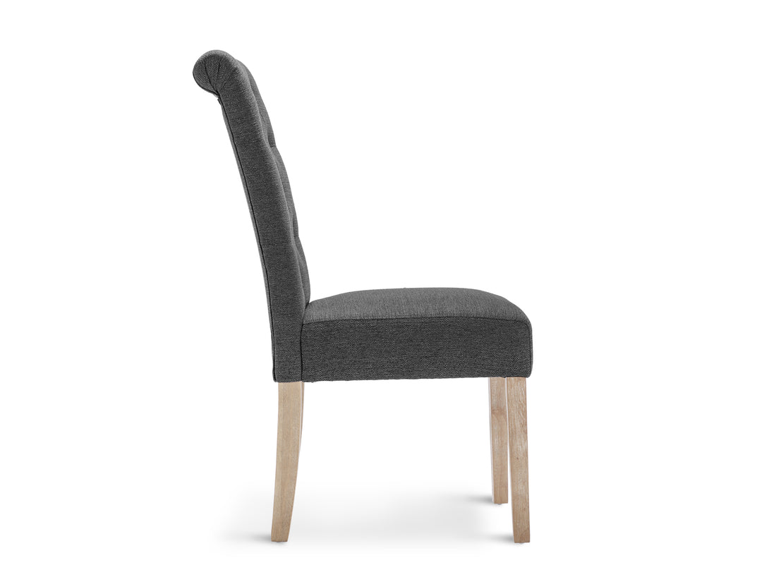 Side view of the Zoey 4 Piece Upholstered Dining Chair in dark grey, showcasing its unique button backrest and wooden legs.